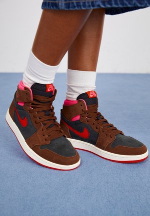 Baskets montantes en daim marron et cuir gris foncé avec accents rouges, semelle intermédiaire blanche et col rose. Caractéristiques lacets noirs et détail logo.