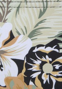 Blumenstoff mit großen Blumen in Creme-, Schwarz- und Goldtönen sowie grünen Blättern; strukturierte Oberfläche und glatte Haptik.