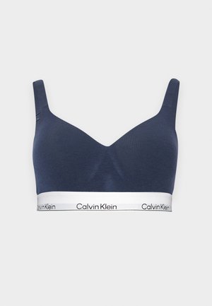 Tengerészkék vezeték nélküli melltartó széles pántokkal és fehér, ismétlődő Calvin Klein logóval díszített elasztikus alsószalaggal.