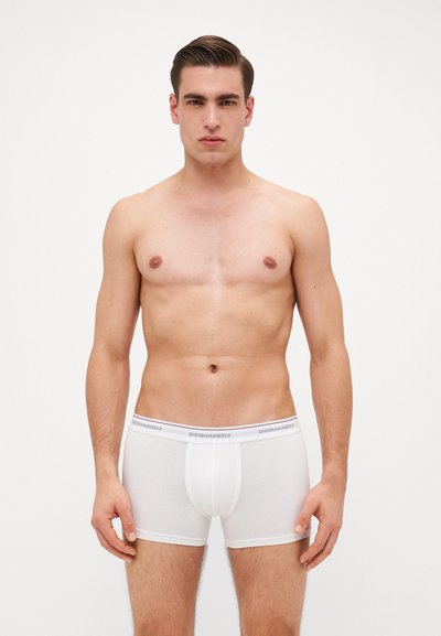 White cotton boxer briefs with a snug fit, featuring a contrasting branded waistband. Smooth texture and mid-thigh length design.