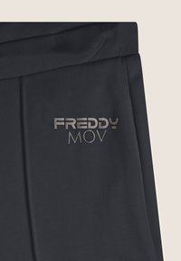 Pantalones deportivos negros con el logo plateado "FREDDY MOV". Presentan una textura suave, un diseño ajustado y una cinturilla elástica para mayor comodidad.