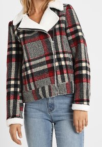 Rutet zip-jakke i rød, sort og creme med krave og manchetter i faux shearling. Lavet af tekstureret stof med oversized pasform.