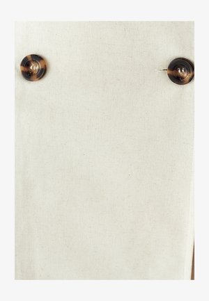 Tela de lino beige con una textura suave, que presenta dos grandes botones de carey como detalles destacados.