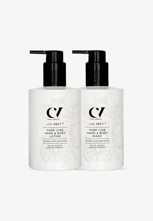 Zwei weiße Pumpflaschen mit der Aufschrift "Age Defy+ Pure Luxe Hand- & Körperlotion" und "Hand- & Körperwaschmittel" mit Duft von Orange und rosa Grapefruit.