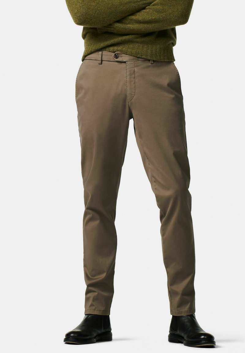 Beige chino pants with a straight fit, featuring a flat front, belt loops, and subtle side pockets. Paired with black ankle boots.