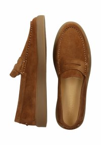 Suedesko i lysebrun med syninger og flad gummisål. Har slip-on stil med en dekorativ rem på den ene side.