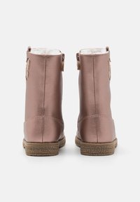 Roze metallic enkelboots met een gestructureerd oppervlak, witte bontvoering en een bruine rubberen zool. Bevat een kleine decoratieve patch aan de achterkant.