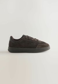 Ciemnobrązowe zamszowe niskie sneakersy z pasującymi sznurówkami i grubą czarną gumową podeszwą na neutralnym tle.