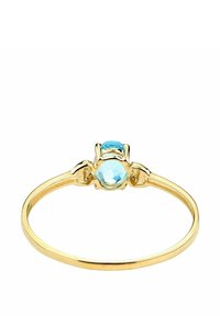 Anillo de oro con una gema redonda de color azul claro engastada en un ajuste de cuatro garras, con una banda delgada y pulida.
