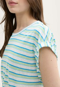 Tricou din bumbac cu dungi, având linii orizontale albastre și verzi pe un fundal alb, cu o croială lejeră și mâneci scurte răsucite.
