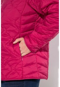 Chaqueta acolchada fucsia con un bolsillo con cremallera en el lateral y texturas de paneles variados, que destaca por un acabado suave y brillante.