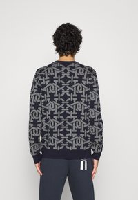 Pullover in maglia di colore blu navy con un motivo geometrico grigio a texture. Presenta polsini e orlo a coste, maniche lunghe e colletto tondo.