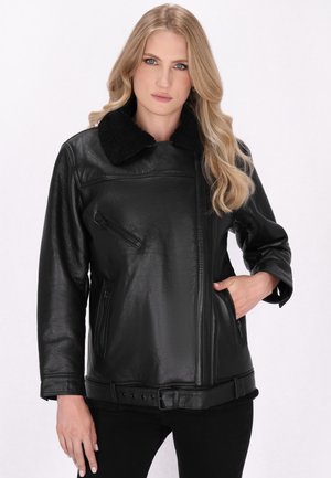 Giacca di pelle nera con colletto in shearling, zip laterale, tasche frontali e vita con cintura. Texture liscia e design aderente.