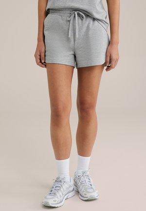 Pantaloni sportivi in misto cotone grigi con elastico in vita e dettaglio con cordoncino, abbinati a calze bianche e sneaker grigie.