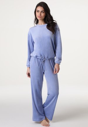 Set di loungewear in velluto morbido color lavanda, composto da un top a maniche lunghe e pantaloni con coulisse, dal taglio rilassato e gambe ampie.