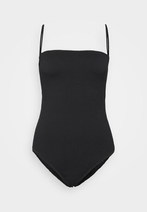 Μαύρο ολόσωμο μαγιό με λεπτές ρυθμιζόμενες τιράντες, ριπ και λεία υφή. Διαθέτει υψηλή γραμμή στα πόδια και μίνιμαλ στυλ.