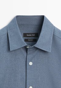 Světle modrá bavlněná košile s výrazným límcem, předním zapínáním na bílé knoflíky a štítkem s nápisem "Massimo Dutti".