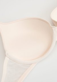 Beżowy wyściełany miseczek biustonosza z siateczkowym bocznym panelem, ukazujący gładką fakturę tkaniny i delikatne wsparcie podtrzymujące.