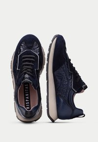 Baskets navy en mélange de daim et de cuir texturé avec une semelle contrastante gris clair, des lacets ronds et un intérieur rembourré.
