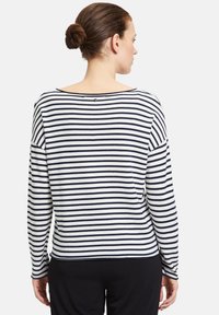 Gestreiftes Langarmoberteil in Weiß und Marineblau. Weicher Stoff, runder Halsausschnitt mit einem Knopfdetail am Rücken. Lockerer Schnitt mit herunterhängenden Schultern.