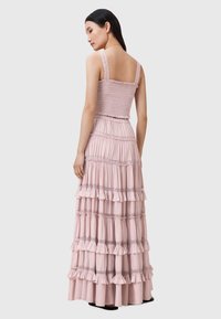 Vestido largo y en capas de suave tela rosa con capas con volantes, corsé fruncido y tirantes anchos. Acabado texturizado con delicados detalles de costura.