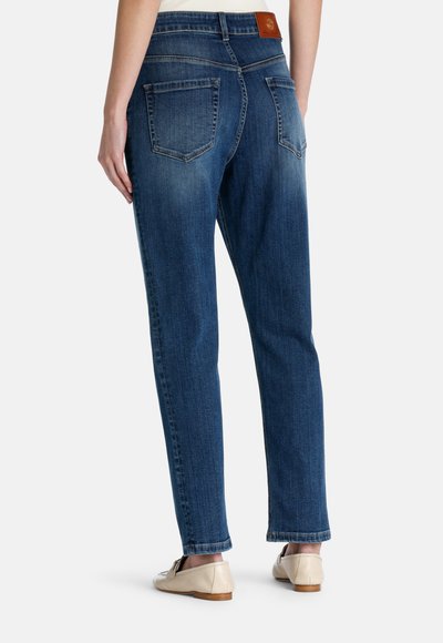 Blue denim jeans with a straight leg fit, five pockets, and a brown leather waistband tag. Features a faded texture along the legs.