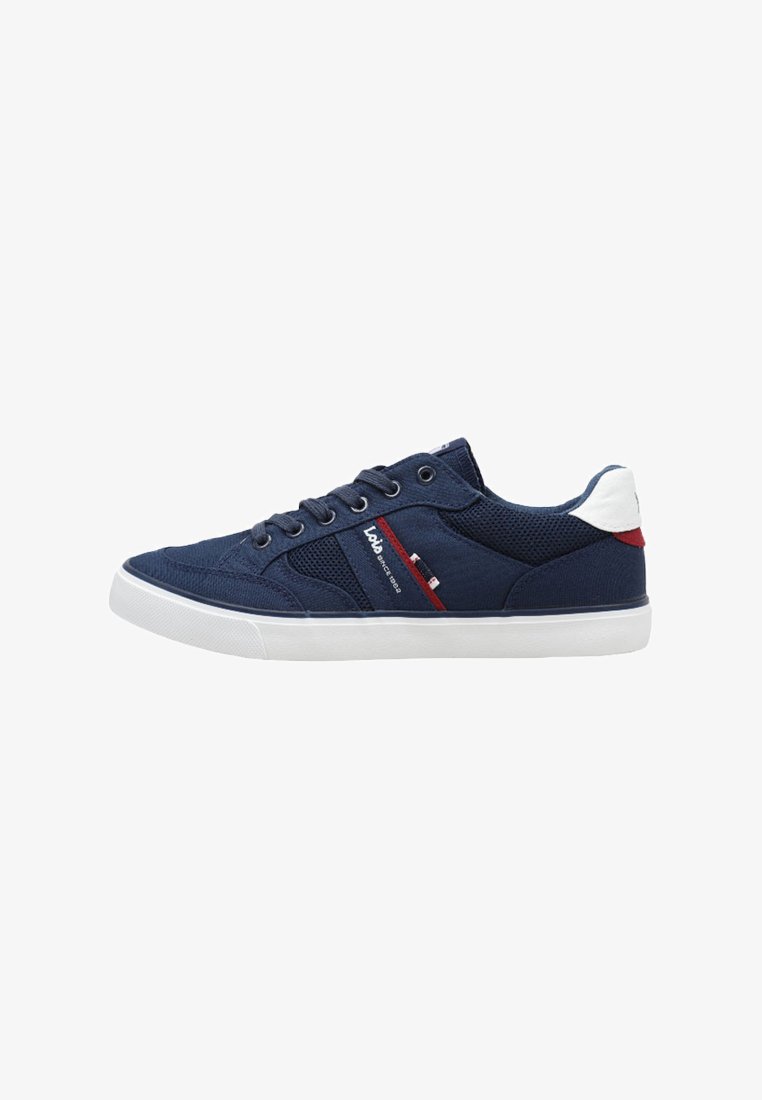Zapatilla baja azul marino con suela blanca, parche blanco en el talón, franja roja y cordones negros, vista lateral.