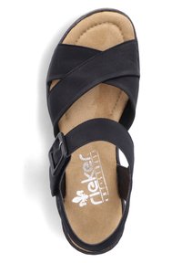 Zwarte sandaal van leer met kruislingse banden, verstelbare gesp en gewatteerde suede binnenzool. Platter zoolontwerp voor comfort.