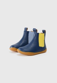 Botas de tobillo de cuero azul con paneles elásticos amarillos y azul claro, suelas marrones y tiradores para ponerlas y quitarlas fácilmente. Textura suave y detalles cosidos.