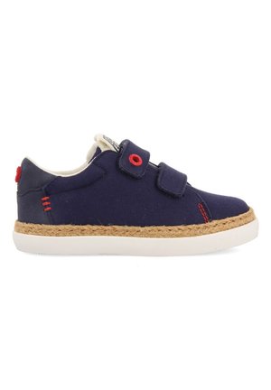 Baskets en toile navy avec deux bandes Velcro, semelle en caoutchouc blanc et détails en jute naturel le long du bord de la semelle. Accents rouges sur le côté.