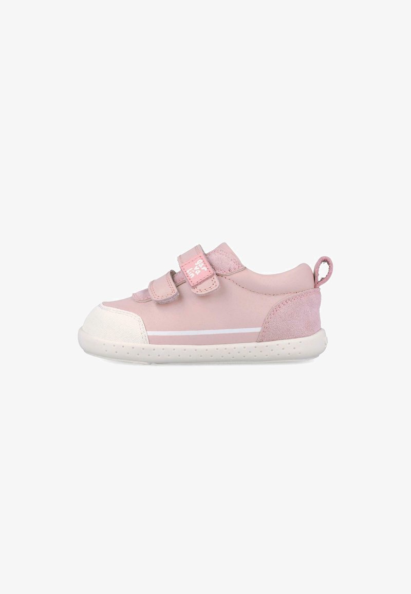 Zapatilla rosa para niño pequeño con dos tiras de velcro, puntera blanca, suela blanca con pequeños puntos y una lengüeta de tela en el talón.