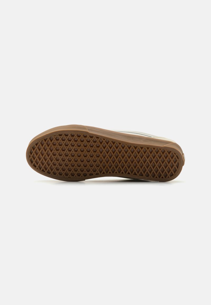 Suela de zapatilla de goma con una superficie texturada en marrón y patrón de diamante, que presenta un borde liso y una forma curva, diseñada para ofrecer tracción.