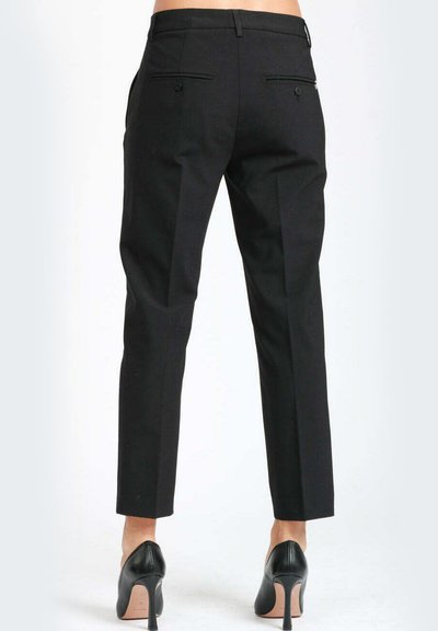 Pantaloni neri su misura alla caviglia con una texture liscia, dotati di due tasche posteriori e un design slim fit. Accompagnati da scarpe con tacco alto.