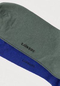 Chaussettes gris et bleu en textile doux. Présentent une texture lisse avec le logo "B. JÖRN BORG" imprimé en noir le long du bord-côte.
