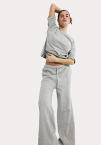 Grijze katoenen cropped t-shirt met een relaxed fit, gecombineerd met grijze joggingbroeken met koordjes, beide zijn gemaakt van een zachte, textuurstof en hebben zijzakken.