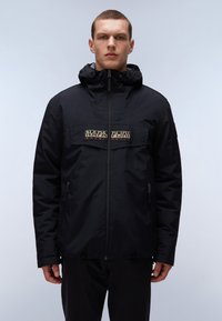 Schwarze Kapuzenjacke mit einem Frontreißverschluss, ausgestattet mit einem kontrastierenden Logo-Patch und Seitentaschen, gefertigt aus einem matten, leichten Material.