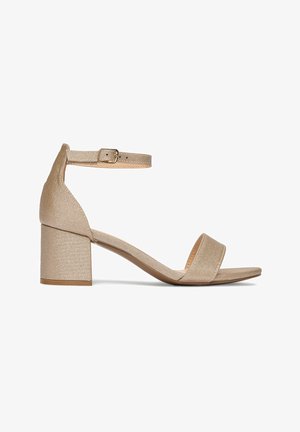 Sandalia beige de punta abierta con tacón ancho y correa ajustable en el tobillo con hebilla, mostrada sobre un fondo blanco.