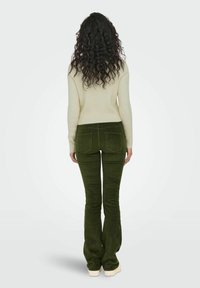 Olive spalvos kordūriniai plačios kišenės kelnių su dviem užpakalinėmis kišenėmis, derinamos su kreminiu raštuotu megztiniu. Modelis parodytas iš nugaros.