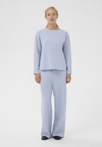 Helehall, pehme, higikanga stiilis pikkade varrukatega ülemine osa ümarate äärega, sobituvate laia jalaga pükstega, mõlemad siledast materjalist.