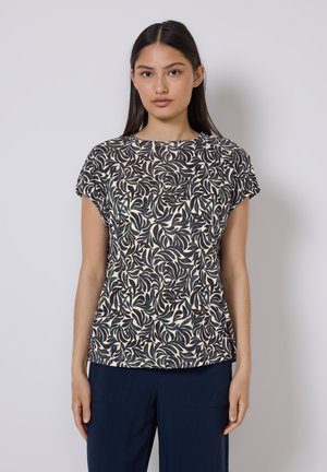 Blusa a maniche corte con scollo rotondo in crema con motivo floreale scuro a foglie, realizzata in tessuto leggero e testurizzato. Design a taglio dritto.