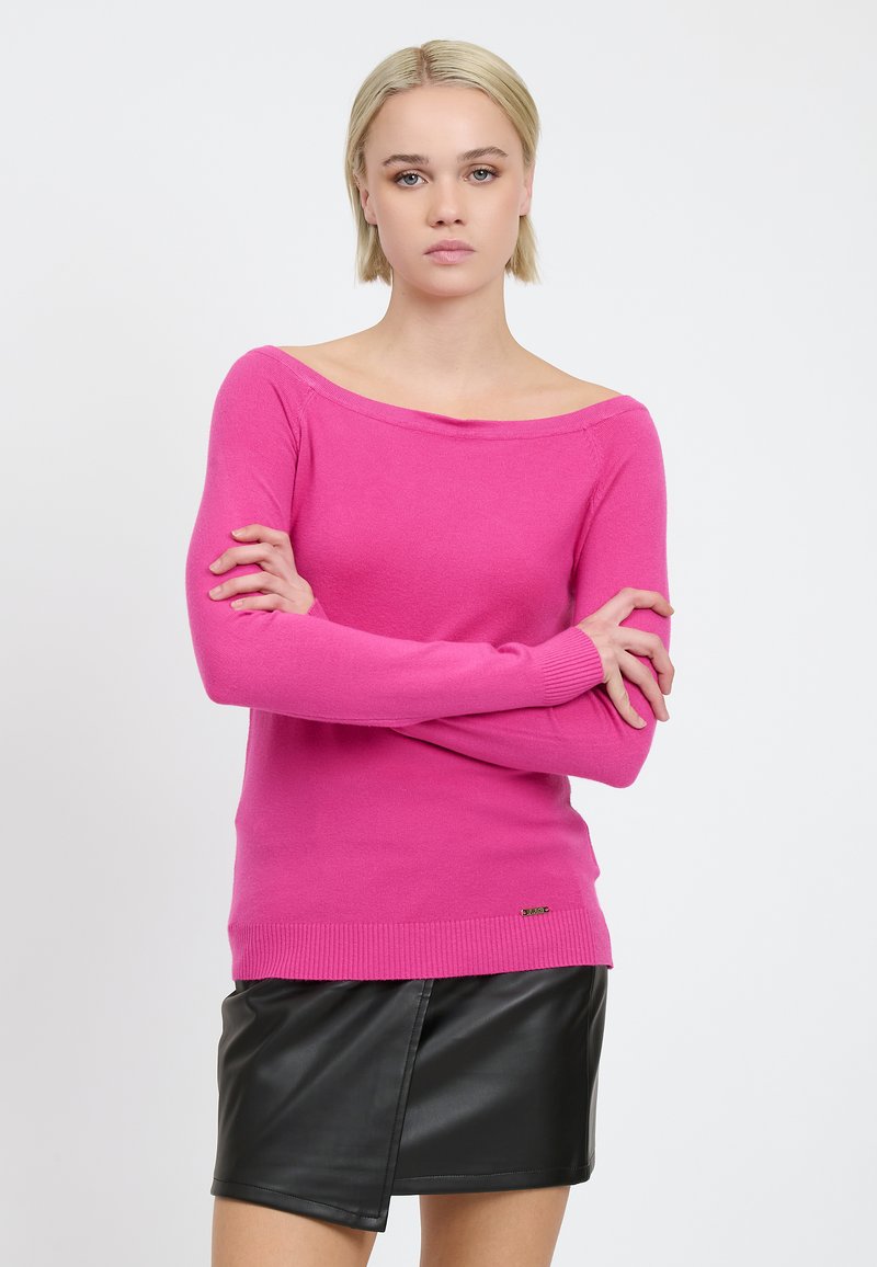 Suéter fucsia sin hombros con mangas largas, puños y dobladillo acanalados, hecho de un material suave, combinado con una mini falda de cuero negra.