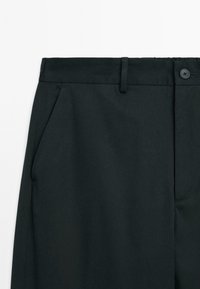 Black tailored pants with front slip pockets, belt loops, button closure, and a zip fly made from smooth fabric.