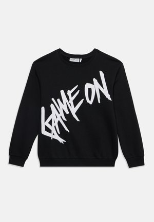Sweat-shirt noir à manches longues et col rond avec un grand texte graphique blanc "GAME ON" en lettres stylisées et inclinées sur le devant.