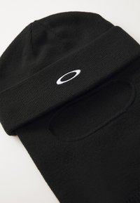 Black knit beanie with an integrated face mask feature. Includes a white embroidered logo on the band, smooth texture, and fitted design.