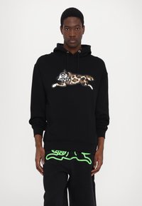 Hoodie noir présentant un design de chat en imprimé léopard dans des tons de marron, blanc et noir. Le tissu semble doux, avec une poche kangourou et des cordons de serrage.