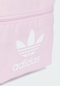 Roza platnena torba s bijelim Adidas logotipom i dizajnom s tri pruge. Teksturirana površina s patentnim zatvaračem.