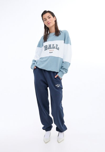 Light blue and white color-blocked sweatshirt with "BALL" text; paired with navy sweatpants featuring logo, smooth cotton fabric, relaxed fit.