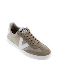 Baskets beiges avec accents blancs, dessus en suède et tissu, fermeture à lacets, semelle en caoutchouc lisse et logo sur la languette.