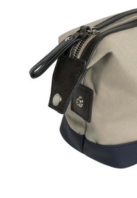 Béžová plátenná taška s tmavými koženými akcentmi a námorníckou spodnou časťou. Obsahuje strieborný zips a detail so zapínaním na druk na boku.