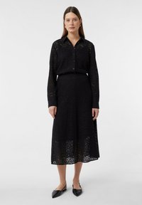 Schwarzes Spitzenoutfit mit einem offenknöpfbaren Hemd und einem passenden Rock. Das Design umfasst aufwendige Muster und einen taillierten Bund.